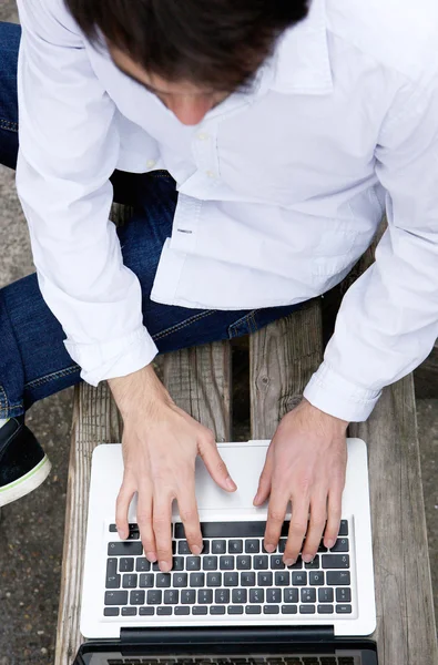 Draufsicht eines jungen Mannes, der auf seinem Laptop tippt — Stockfoto