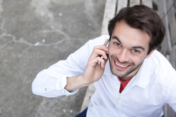 Gelukkig jonge man die door mobiele telefoon buitenshuis — Stockfoto