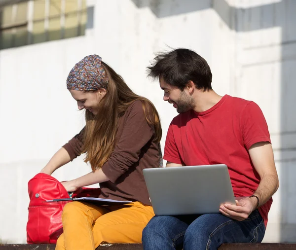 Dos estudiantes felices sentados al aire libre con ordenador portátil —  Fotos de Stock