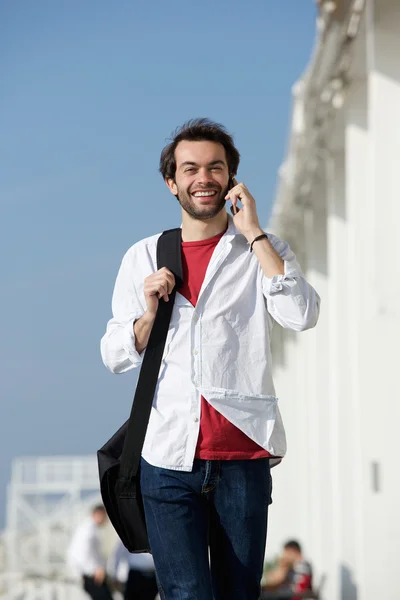 Glad ung man promenader och talar i mobiltelefon — Stockfoto