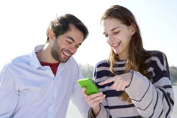 Jong koppel glimlachen en kijken naar mobiele telefoon — Stockfoto