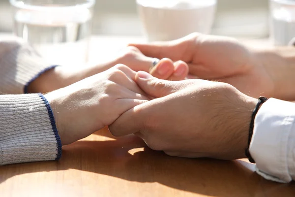 Male and female holding hands over table — Stock Photo, Image