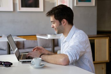 Bilgisayarda çalışan mutlu genç adam. 