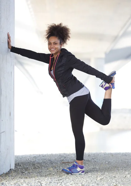 Mujer joven sosteniendo ejercicio de pierna entrenamiento — Foto de Stock