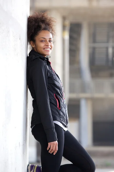 Smiling sports woman relaxing leaning against wall — Stock Photo, Image