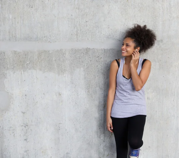 Jovem mulher esportiva sorrindo com fones de ouvido — Fotografia de Stock