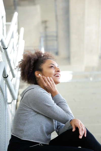 Young woman sitting listening to music with earphones — Stock Photo, Image