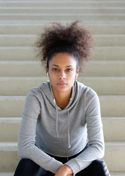 Unga afroamerikanska kvinnan sitter på stegen med hörlurar — Stockfoto