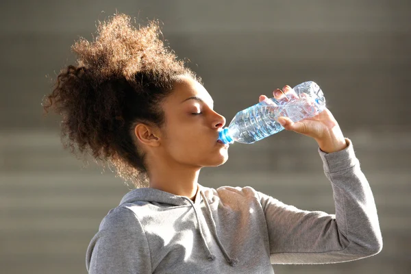 魅力的な若い女性は、ボトルから水を飲む — ストック写真