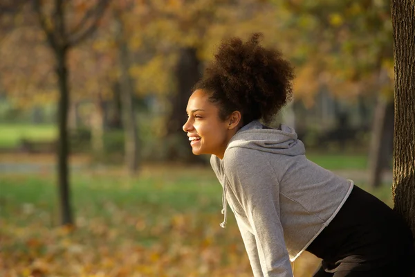 Jovem mulher sorrindo e descansando após o treino no parque — Fotografia de Stock