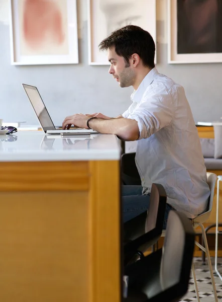 Młody człowiek wpisując na laptopie internet Café — Zdjęcie stockowe