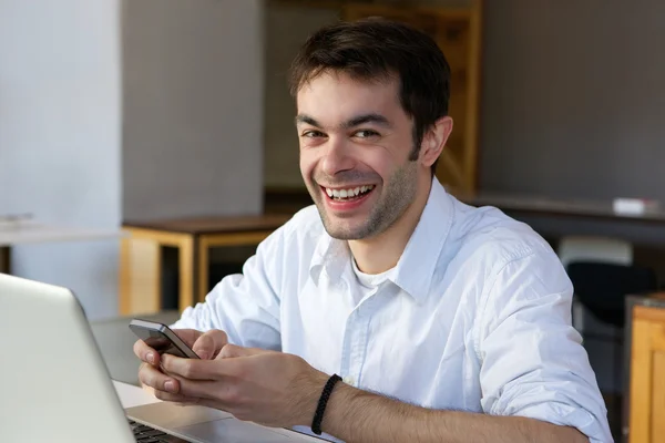 Glimlachend jonge man het verzenden van tekstbericht op mobiele telefoon — Stockfoto