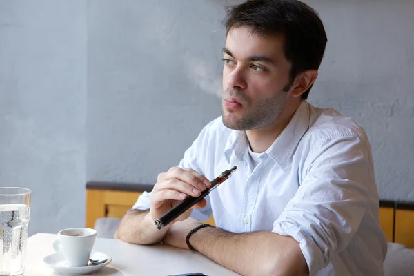 Young man smoking e cigarette indoors — Stock Photo, Image