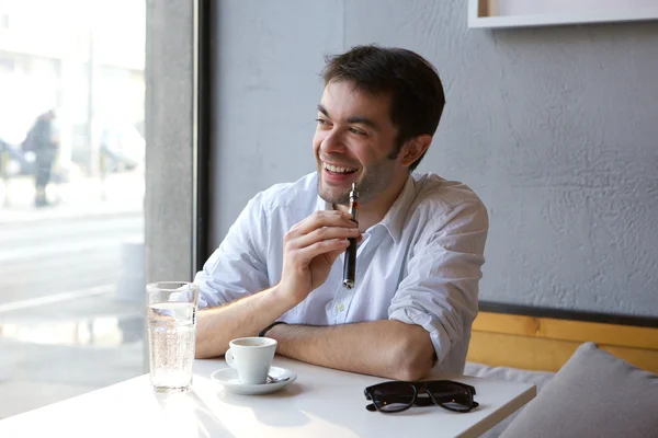 Jovem sorrindo com e cigarro dentro de casa — Fotografia de Stock