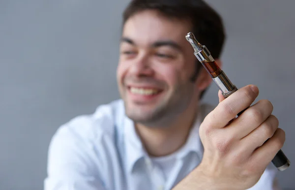 Jeune homme souriant avec cigarette électrique — Photo