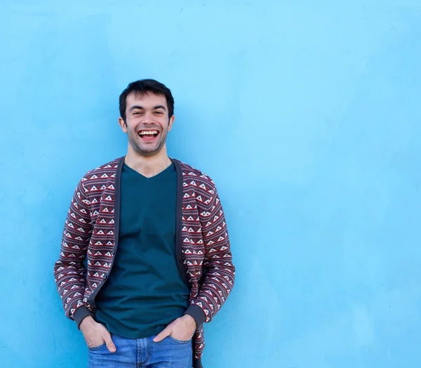 Junger Mann lacht vor blauem Hintergrund — Stockfoto