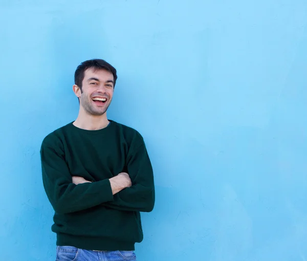 Knappe jonge man die lacht tegen blauwe achtergrond — Stockfoto