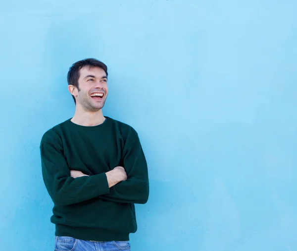 Happy young man laughing against blue background — Stock Photo, Image