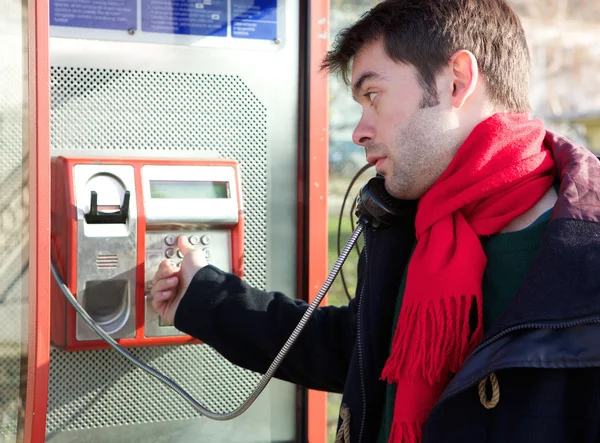 Junger Mann wählt Telefonnummer an öffentlicher Telefonzelle — Stockfoto