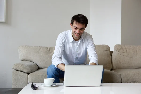 Młody człowiek pracuje w domu z laptopem — Zdjęcie stockowe