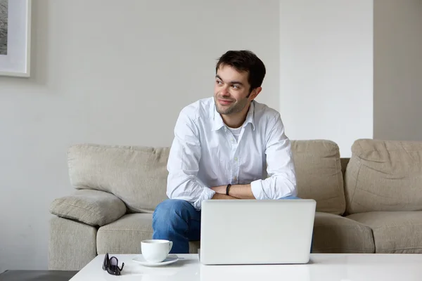 Jovem sentado em casa com laptop — Fotografia de Stock