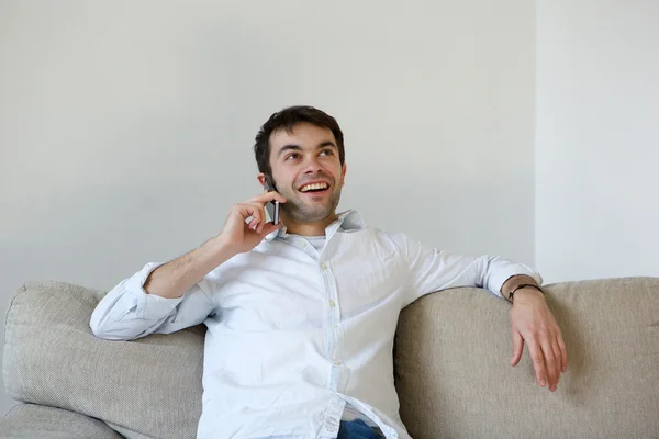 Hombre joven relajándose en casa llamando por teléfono móvil — Foto de Stock