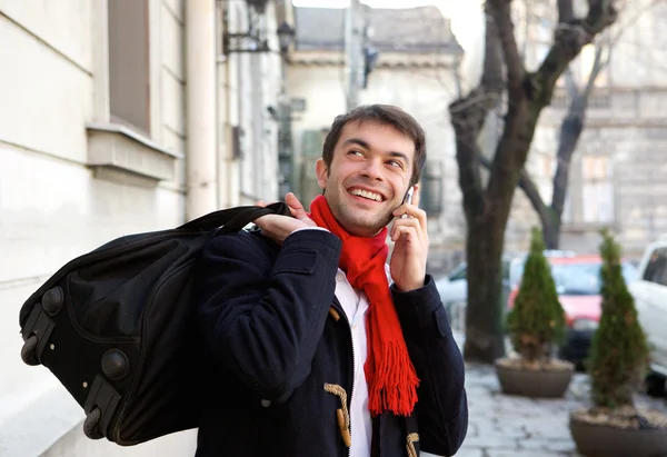 Jeune homme voyageant avec sac appelant par téléphone mobile — Photo