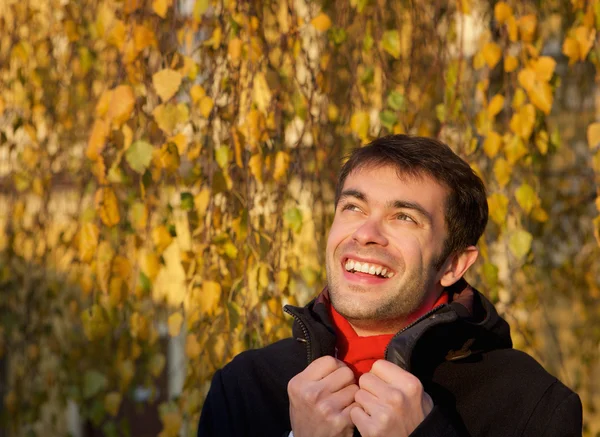 Gelukkig jonge man die lacht buitenshuis met winter jas — Stockfoto