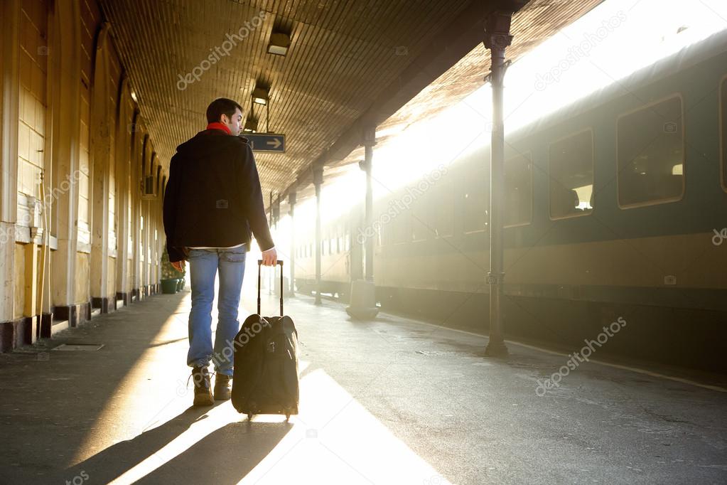 Young man walking with bag at train station