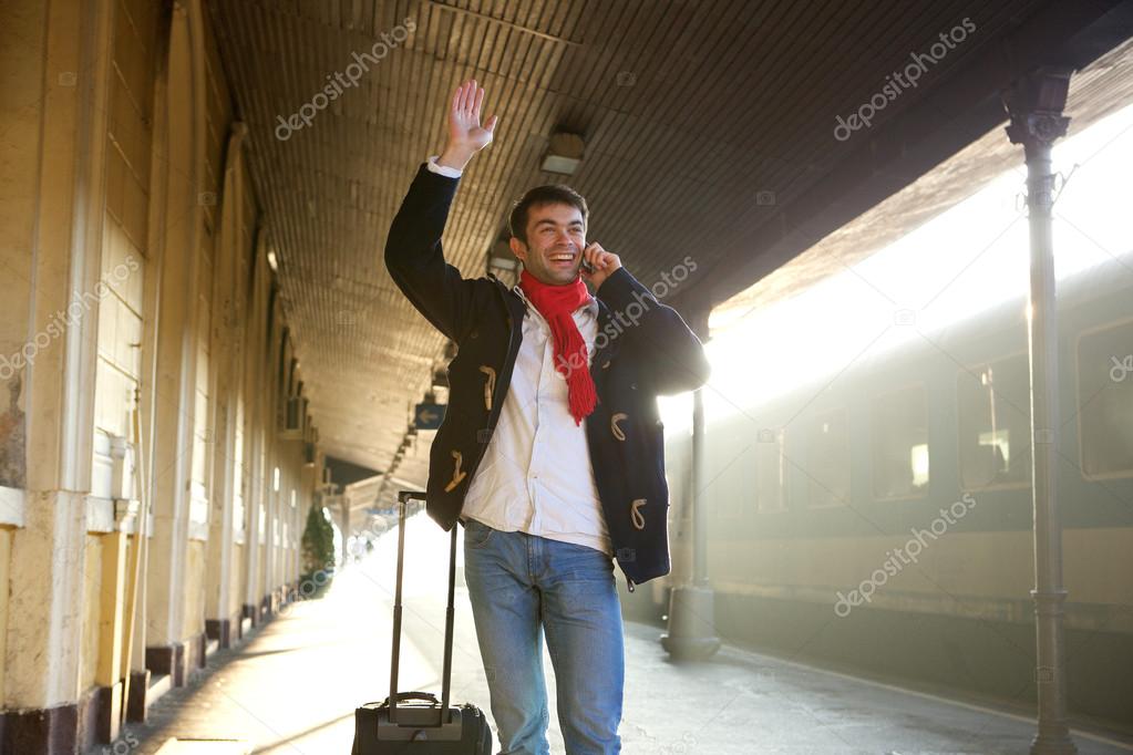 Young man waving hand at train station