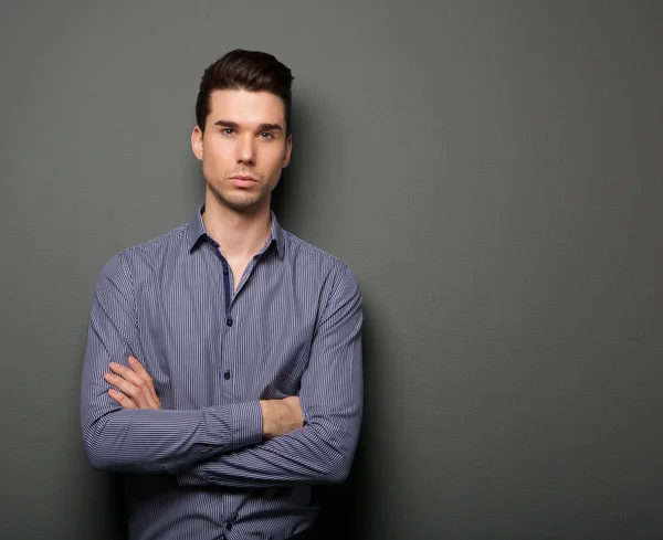 Retrato de un joven guapo posando con los brazos cruzados — Foto de Stock