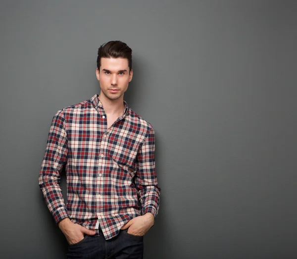 Relaxed young man with checkered shirt posing — Stock Photo, Image