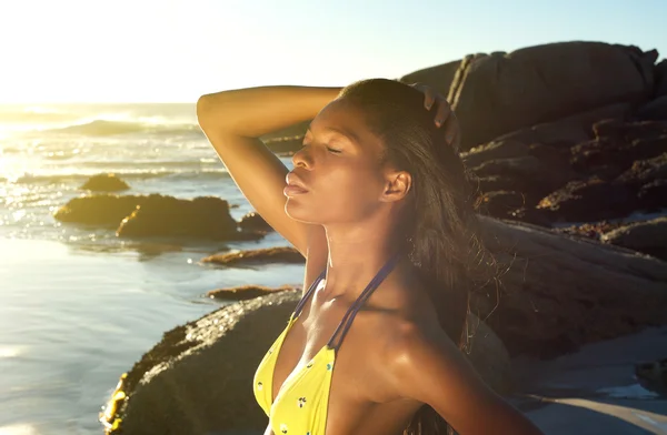 Mujer africana posando con la mano en el pelo en la playa — Foto de Stock