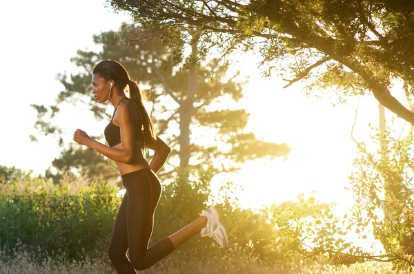 Vista lateral joven mujer negra corriendo en la naturaleza — Foto de Stock