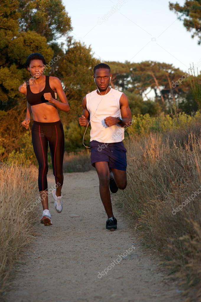 Healthy young black couple running together outdoors