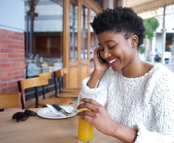 Smiling young woman talking on mobile phone at restaurant — Stock Photo, Image