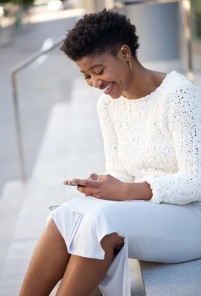 Kvinna sitter utomhus sändande meddelande på mobiltelefon — Stockfoto