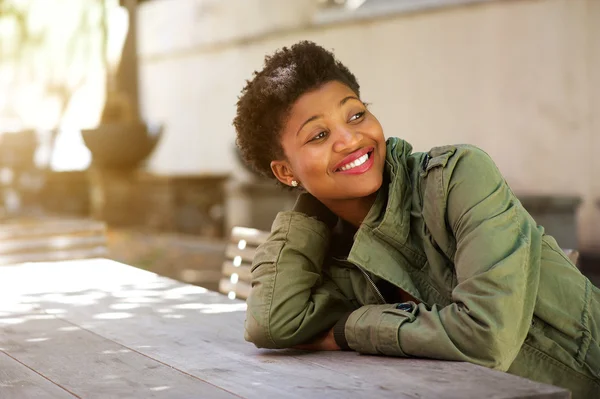 Mladá žena sedí venku a s úsměvem — Stock fotografie