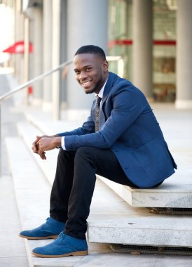 Açık havada basamaklarında oturan işadamı gülümseyen