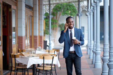 Yürüyüş ve cep telefonu üzerinde konuşurken samimi işadamı