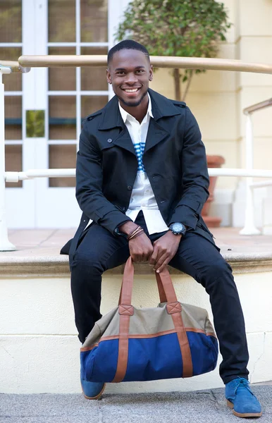 친절 한 젊은 남자가 가방을 호텔 밖에 서 앉아 — 스톡 사진