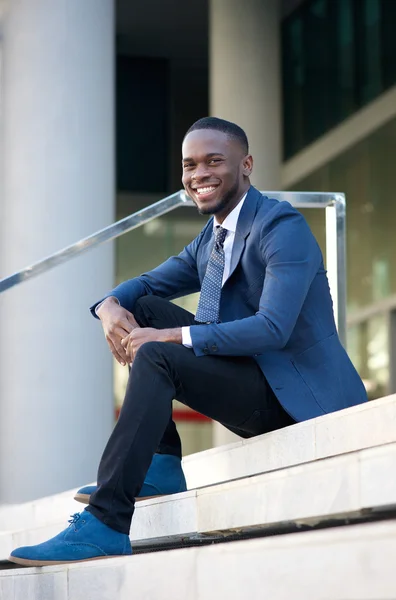 Friendly young businessman sitting on steps in the city — Stock Photo, Image