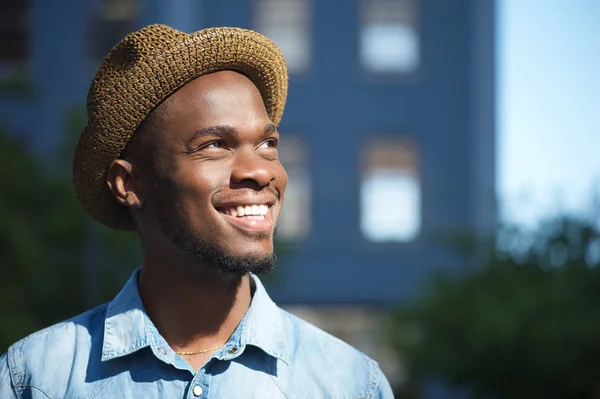 Glücklicher afrikanisch-amerikanischer Mann, der draußen mit Hut lächelt — Stockfoto