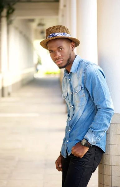 Hombre joven relajado con sombrero apoyado en la pared al aire libre — Foto de Stock