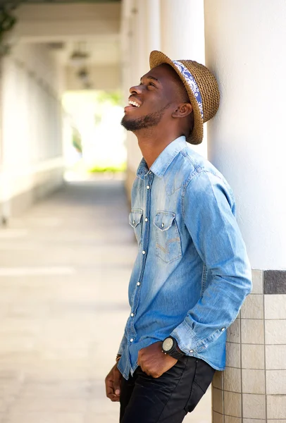 Feliz joven apoyado en la pared riendo — Foto de Stock