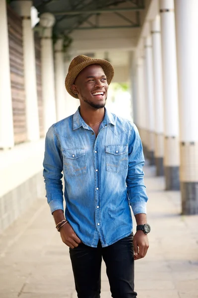 Beau jeune homme heureux marchant dehors avec un chapeau — Photo