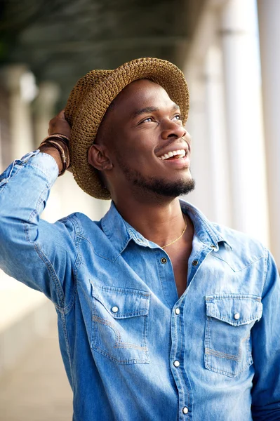 Carefree young african american man smiling with hat — Stock Photo, Image