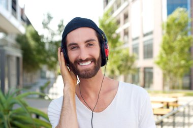 Neşeli genç adam açık havada kulaklıklar ile