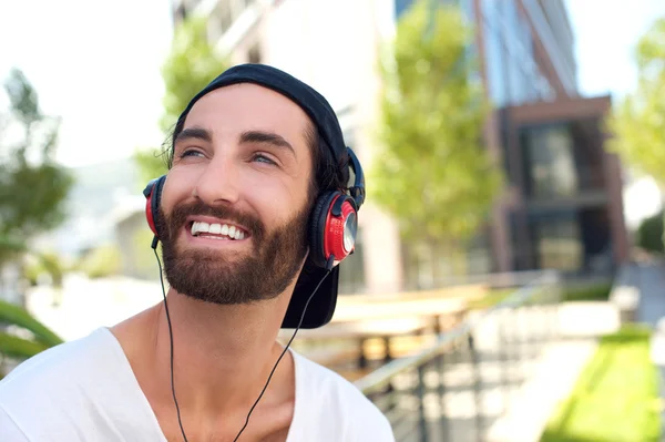 Pohledný mladý muž s úsměvem se sluchátky — Stock fotografie