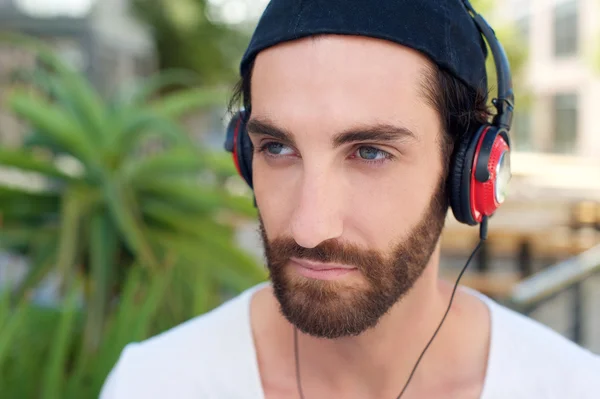 Man with beard listening to music on headphones — Stock Photo, Image